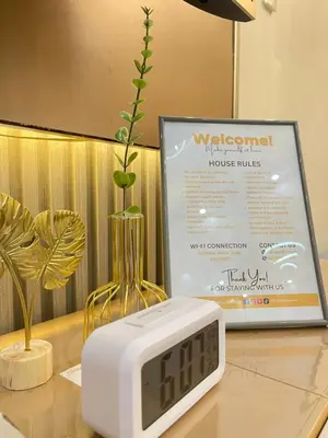 a clock on a table next to a vase with a plant at Orchids Shore Residences Direct Pool Access in Manila