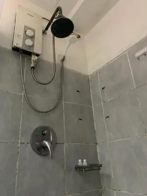 a bathroom with a shower with a fan and a sink at Sea Residence in Manila