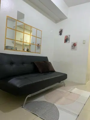 a black couch in a living room with a mirror at Ballentos staycation in Manila