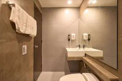 a bathroom with a sink and a toilet and a mirror at Victoria Court Suites - Pasig in Manila