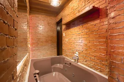 a bath tub in a room with a brick wall at Victoria Court Suites - Pasig in Manila