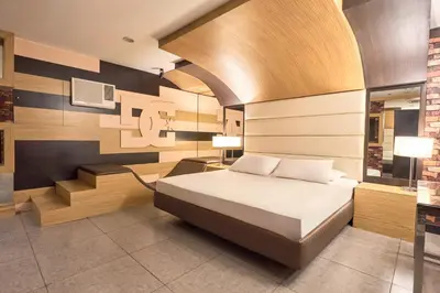 a bedroom with a bed and a desk with two lamps at Victoria Court Las Pinas in Manila