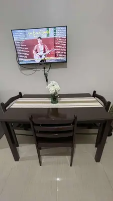 a table with a tv on a wall with flowers on it at AJ Staycation at Shore 1 Residences Tower D in Manila