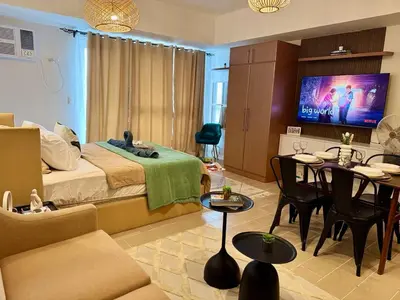 a bedroom with a bed and a living room with tables at Cozy Staycation Venice with Balcony Mckinley near Bgc in Manila