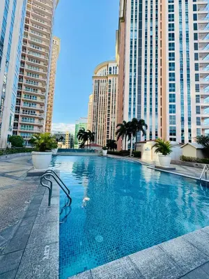 a large swimming pool in a city with tall buildings at Cozy Staycation Venice with Balcony Mckinley near Bgc in Manila