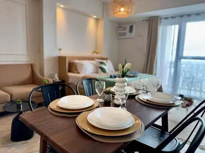 a dining room table with plates and wine glasses at Cozy Staycation Venice with Balcony Mckinley near Bgc in Manila