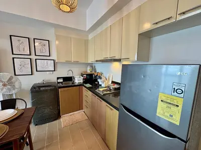 a kitchen with a stainless steel refrigerator and a table at Cozy Staycation Venice with Balcony Mckinley near Bgc in Manila