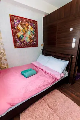 a bedroom with a bed with pink sheets and a picture on the wall at Chic Romantic Getaway Makati Studio One BR Two BR Swim Gym 300 MB in Manila