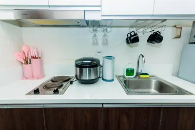 a kitchen counter with a sink and a stove at Chic Romantic Getaway Makati Studio One BR Two BR Swim Gym 300 MB in Manila
