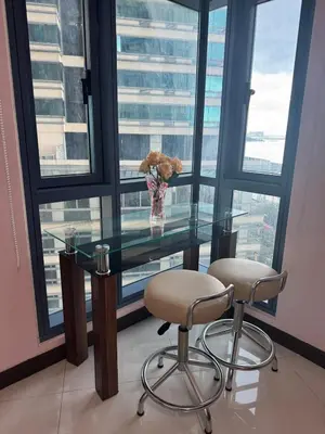 a glass table with two chairs and a vase of flowers at Grand Riviera Suites 1201 Near US Embassy and St Luke's Medical Center Extension Clinic SLEC by Prime Stay in Manila