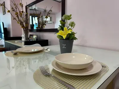 a table with two plates and a bowl and a vase with flowers at Grand Riviera Suites 1201 Near US Embassy and St Luke's Medical Center Extension Clinic SLEC by Prime Stay in Manila