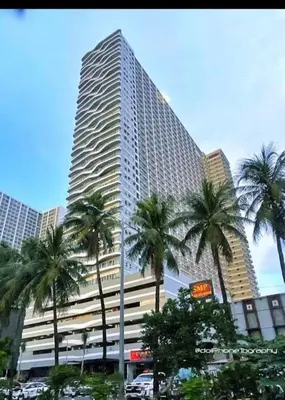 a tall building with palm trees in front of it at Casa Alia at Coast - near MOA, US Embassy, PICC, WTC in Manila