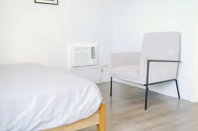 a bedroom with a white bed and a chair at Cozy 2-Bedroom at South of Market SOMA BGC near SM Aura, Market! Market! & Bonifacio High Street in Manila