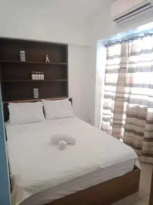 a bedroom with a large white bed with a headboard at 1633 pool view 2br in Manila