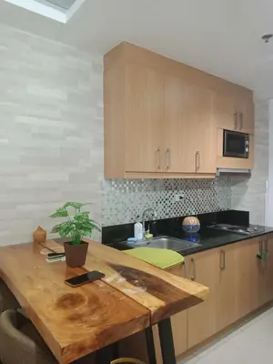 a kitchen with wooden cabinets and a wooden table at 1633 pool view 2br in Manila