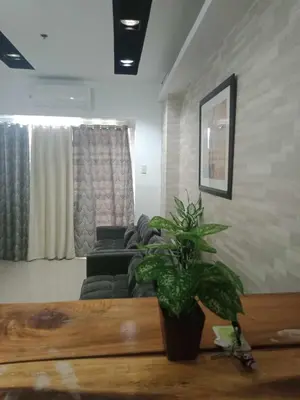a living room with a couch and a plant on a table at 1633 pool view 2br in Manila