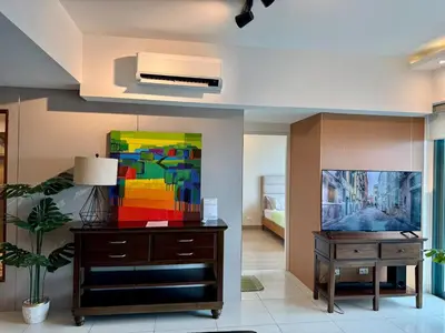 a living room with a tv and a table and a painting at BGC One Uptown Premium 2BR Suite with Balcony near Supermarket, Malls and Restaurants in Manila