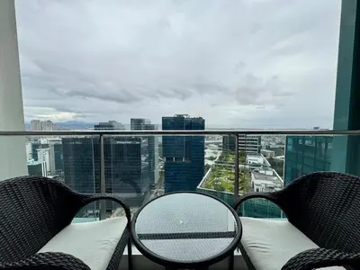 a balcony with two chairs and a table and a view at BGC One Uptown Premium 2BR Suite with Balcony near Supermarket, Malls and Restaurants in Manila