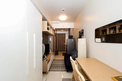 a kitchen and dining room with a table and a refrigerator at Charlie's Staycation at Coast Residences in Manila