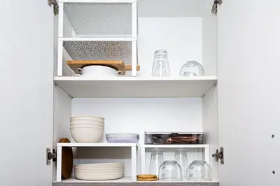 a kitchen cabinet filled with dishes and other kitchen items at Charlie's Staycation at Coast Residences in Manila