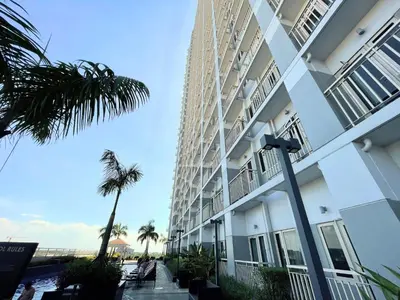 a large white building with a palm tree next to it at Charlie's Staycation at Coast Residences in Manila