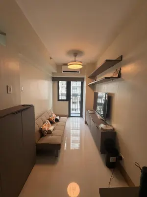 a living room with a couch and a television at Shore 3 Tower 3 1BD - MOA Complex in Manila