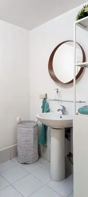 a white bathroom with a sink and a mirror at Charming Modern Condo in BGC in Manila