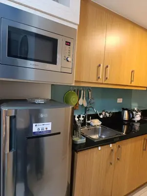 a kitchen with a microwave and a sink at Shell Residences - MOA in Manila