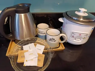 a counter with a coffee pot and three coffee cups at Shell Residences - MOA in Manila