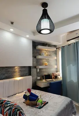 a living room with a bed and aendant light at Shell Residences - MOA in Manila