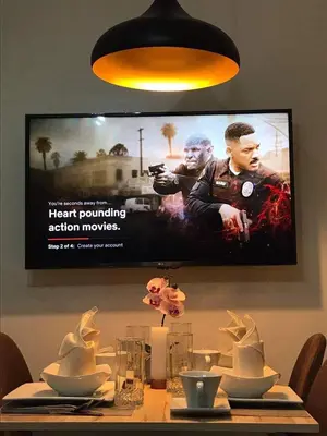 a television hanging on a wall above a dining table at Shore B 524 in Manila