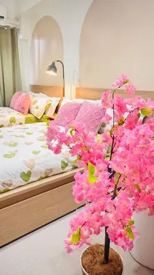 a bedroom with a bed and a tree with pink flowers at Japanese Inspired Hotel at MOA in Manila