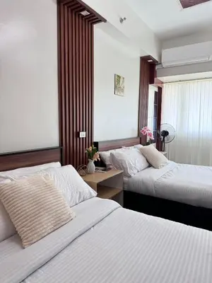 a bedroom with two beds and a table and a window at 2 Bed's Unit at PICC Near MOA in Manila