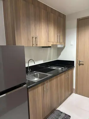 a kitchen with a sink and wooden cabinets at Shore Residence Tower 1 Staycation in Manila
