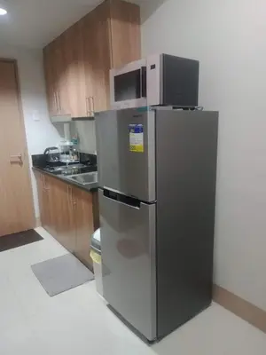 a kitchen with a stainless steel refrigerator with a microwave at Shore Residence Tower 1 Staycation in Manila