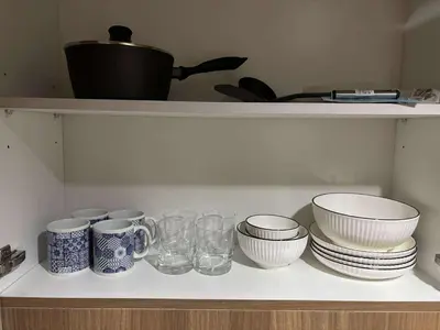 a shelf with bowls and plates and glasses on it at Shore Residence Tower 1 Staycation in Manila