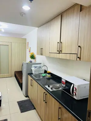 a kitchen with wooden cabinets and a microwave at Apartment Rm# 839 B shore 1 in Manila