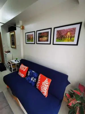 a blue couch in a living room with pillows on it at Shore 3 tower 2 mall of Asia staycation in Manila