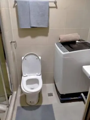 a bathroom with a toilet and a sink and towels at SMDC Apartment in FAME in Manila