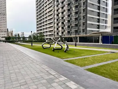 a metal sculpture in a park with tall buildings at SMDC Fame Residences in Manila