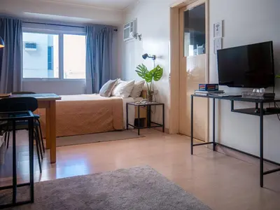 a room with a bed and a desk with a television at Private Modern Condo in BGC in Manila