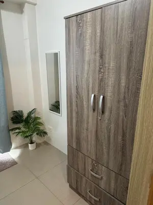 a wooden cabinet in a room with a potted plant at Shore Residence by CozyHaven's Homestay in Manila