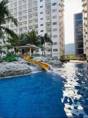 a water slide in the middle of a pool with buildings at Shore Residence by CozyHaven's Homestay in Manila
