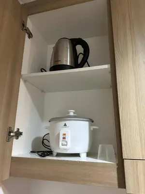 a slow cooker sitting on a shelf in a cabinet at Shore Residence by CozyHaven's Homestay in Manila