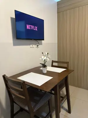 a table and chairs with a television on a wall at Shore Residence by CozyHaven's Homestay in Manila