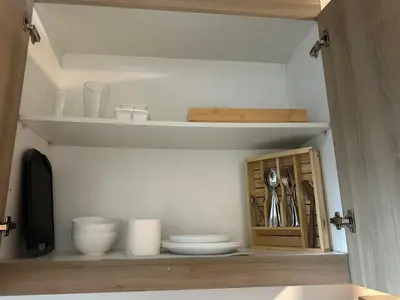 a cupboard with bowls and plates in a kitchen at Shore Residence by CozyHaven's Homestay in Manila