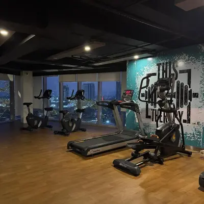 a gym with several tread machines in a room at Elegant 1BR with Great View, Panoramic Pool Near Ortigas CBD - 24 in Manila