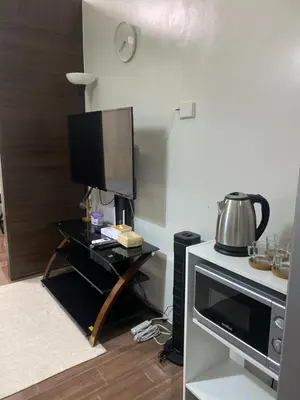 a living room with a tv and a table with a microwave at Casa Beatrice Staycation in Manila