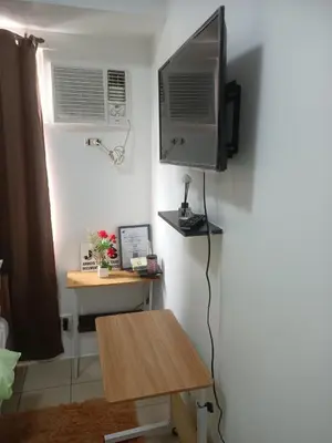 a room with a tv on a wall with a table at Urban deca tower by jas airways in Manila