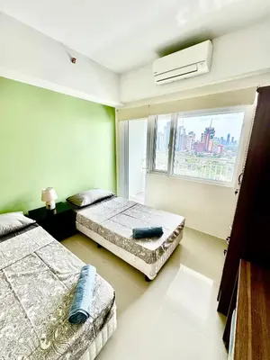 two beds in a room with a window at Jazz Residences Makati in Manila